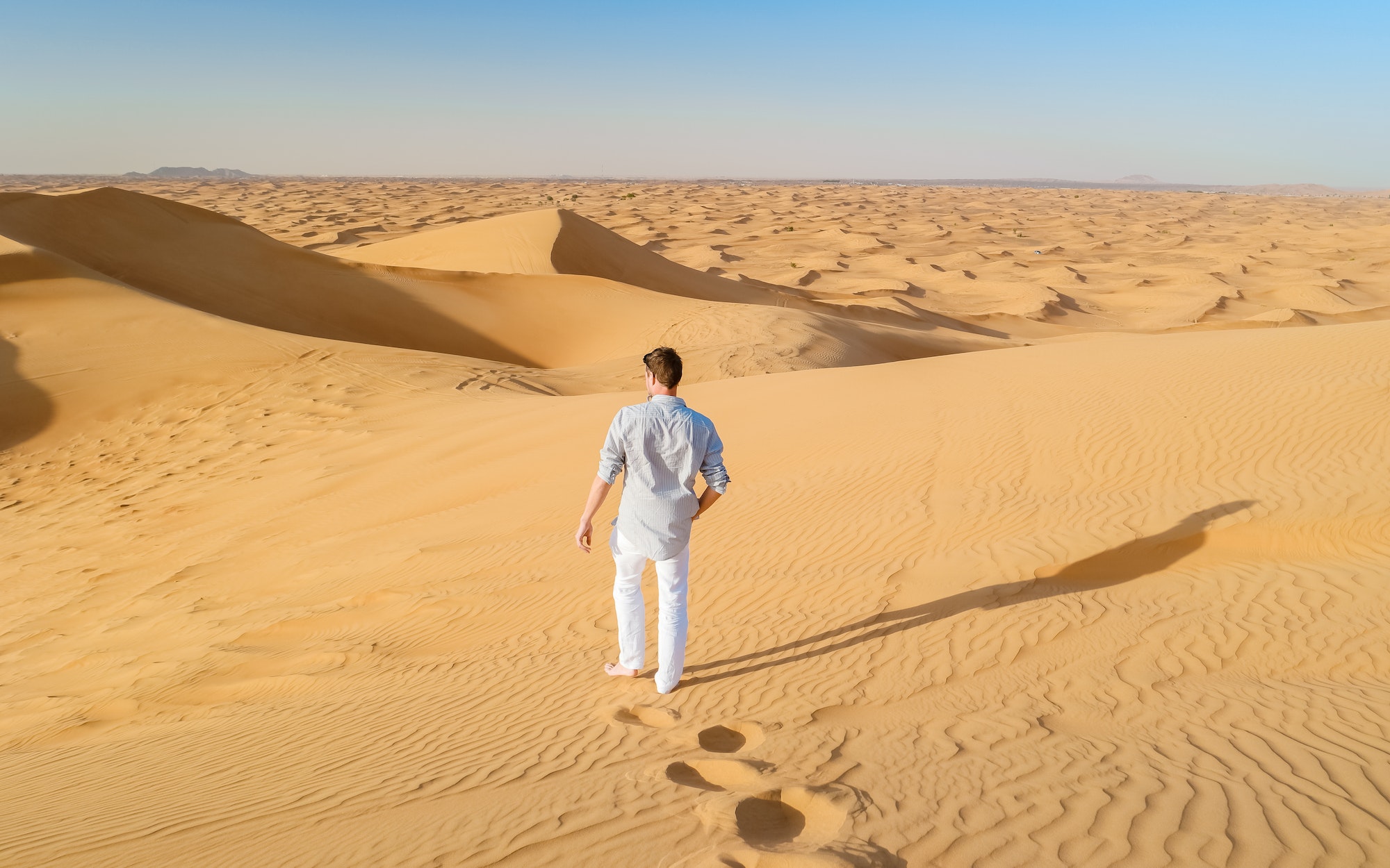 Young men walking in the desert of Dubai, Sand dunes of Dubai United Arab Emirates