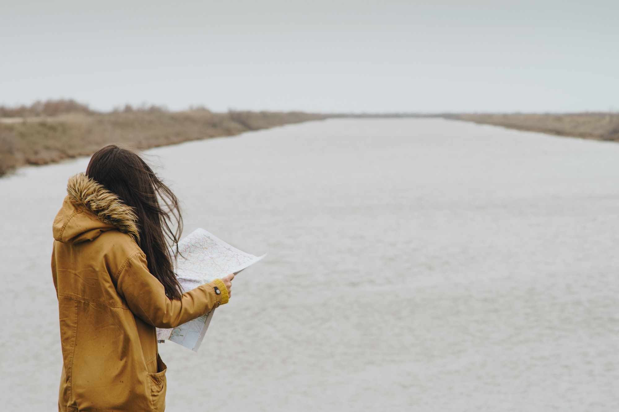 Woman reading a map next to a river, Greece.