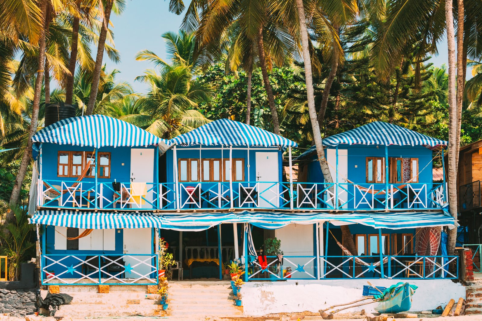 Canacona, Goa, India. Famous Painted Guest Houses On Beach Against Background Of Tall Palm Trees In